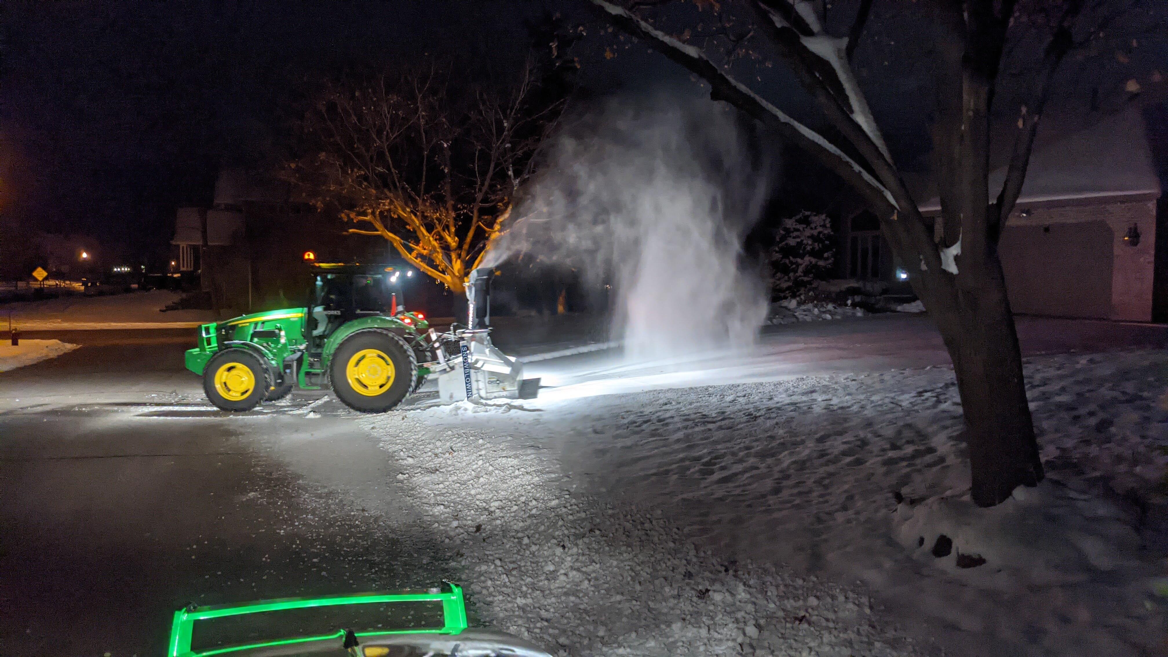 An Iceworks tractor with an inverted snowblower clearing a driveway to the edge